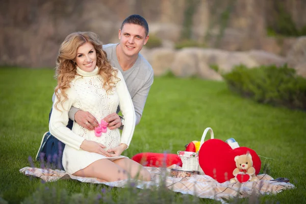 Zwangere vrouw en haar echtgenoot ontspannen op aard en hebben picknick in park — Stockfoto