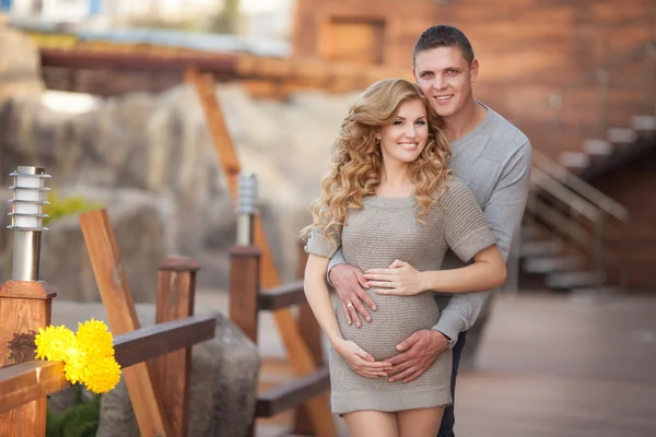 Young pregnant woman with husband walking outdoor and hugs tummy — Stock Photo, Image