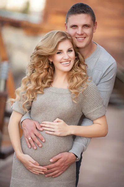 Young pregnant woman with husband walking outdoor and hugs tummy — Stock Photo, Image