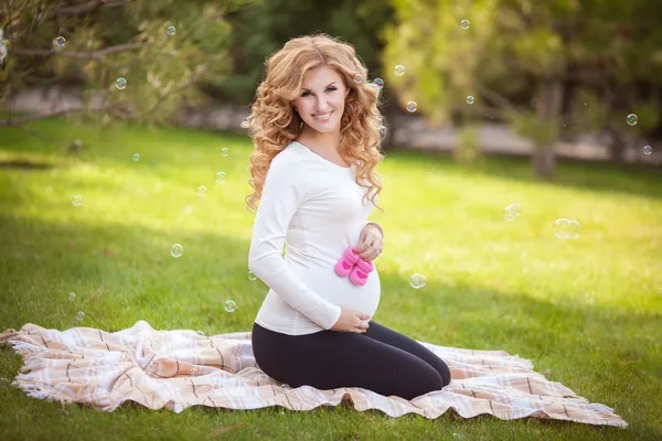 Gelukkig jonge zwangere vrouw buitenshuis in voorjaar groen park — Stockfoto