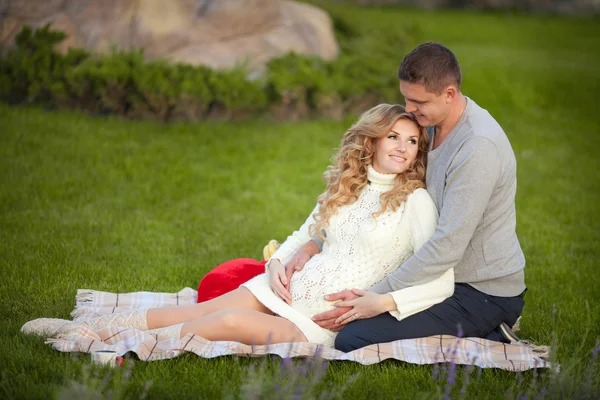 Pregnant woman and her husband relaxing on nature and have picnic in park — Stock Photo, Image