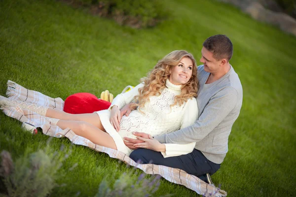 Mujer embarazada y su marido relajarse en la naturaleza y hacer un picnic en el parque —  Fotos de Stock