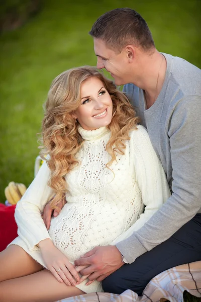 Zwangere vrouw en haar echtgenoot ontspannen op aard en hebben picknick in park — Stockfoto