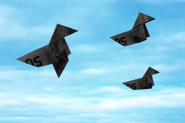 Black bank note origami birds flying away on blue sky — Stock Photo, Image
