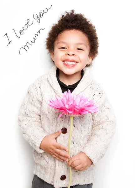 Kind mit großem Lächeln und großer rosafarbener Blume mit i love Mama-Botschaft — Stockfoto