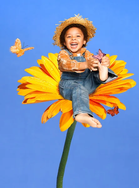 Kelebekler gülüyor oynayan büyük bir çiçek üzerinde oturan çocuk — Stok fotoğraf