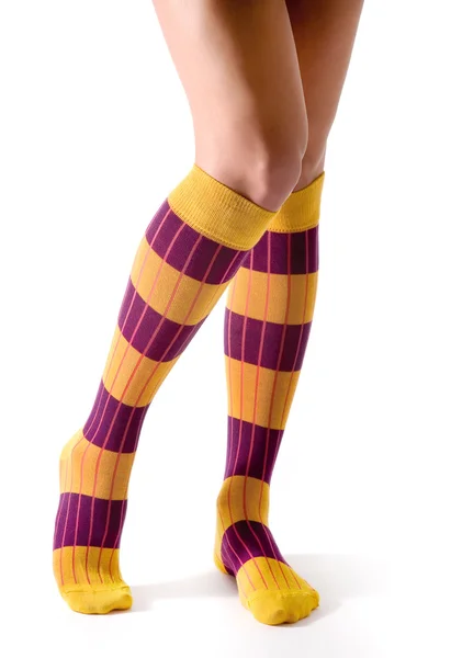 Νεαρή γυναίκα τα πόδια ποζάρει με μοβ και κίτρινο ριγέ κάλτσες — Φωτογραφία Αρχείου