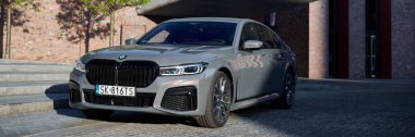 Gri BMW 740D xDrive NOSPR konser salonunun önünde. 340 HP motoru, hız 0-100 km / saat - 5s Katowice, Polonya, 12.06.2021