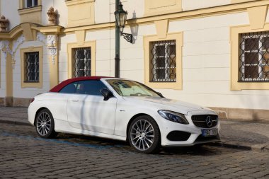 Üstü açık, kırmızı çatılı beyaz bir Mercedes C sınıfı. Prag 'ın eski kasabasında bir apartman evinin yanına park edilmiş. Ön manzara. Prag, Çek Cumhuriyeti, 01.30.2017