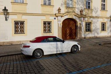 Üstü açık, kırmızı çatılı beyaz bir Mercedes C sınıfı. Prag 'ın eski kasabasında bir apartman evinin yanına park edilmiş. Dikiz aynası. Prag, Çek Cumhuriyeti, 01.30.2017
