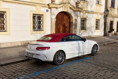 Üstü açık, kırmızı çatılı beyaz bir Mercedes C sınıfı. Prag 'ın eski kasabasında bir apartman evinin yanına park edilmiş. Dikiz aynası. Prag, Çek Cumhuriyeti, 01.30.2017