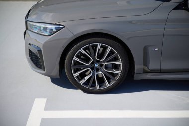 Boş bir otoparka park edilmiş gri bir BMW 740 'ın tekerleği. Başka araba ve insanlar yok. Katowice, Polonya, 12.06.2021
