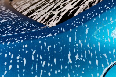 Araba tamiri. Araba yıkamada yıkarken köpükle kaplı bir araba parçası..