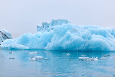 İzlanda 'da mavi bir buzdağı. Jokulsarlon gölüne akan bir buzdağı, buzulun ön tarafından ayrılmış..