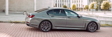 Lüks gri BMW 740 D, modern bir ofis binasının yanına park edilmiş. Yan görüş. Başka araba ve insanlar yok. Katowice, Polonya, 12.06.2021