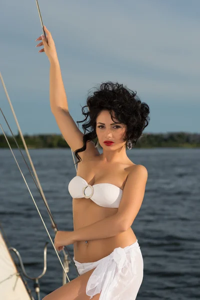 Junge Frau im Badeanzug steht an sonnigem Tag auf Jacht — Stockfoto