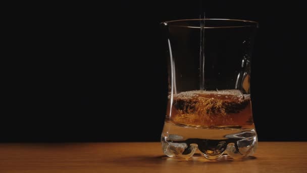 Drank of whisky gegoten in een glas tegen zwarte achtergrond — Stockvideo