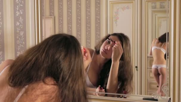 Girl paints eyelashes before a mirror — Stock Video