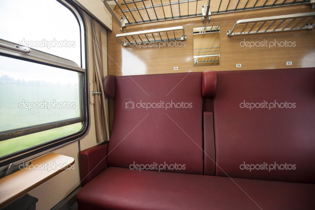 Train compartment with red seats and a view out the window