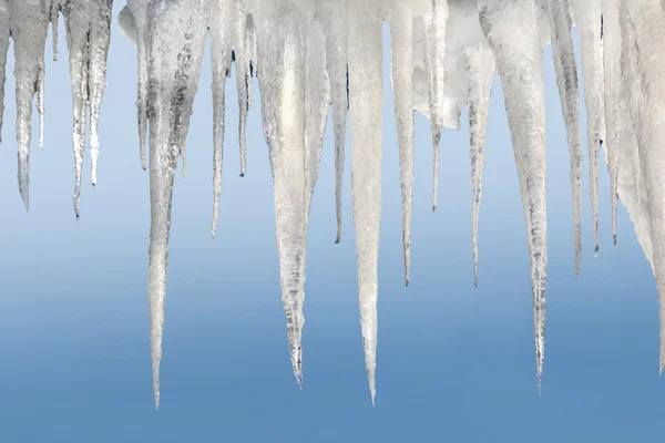 Aantal natuurlijke ijspegels op een bleke blauwe achtergrond — Stockfoto