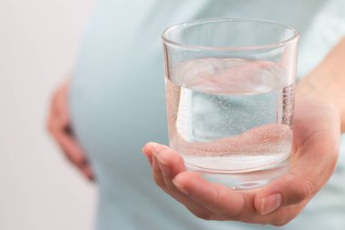 Pregnant woman holding the glass cup of water