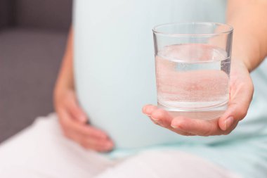 Pregnant woman holding the glass cup of water