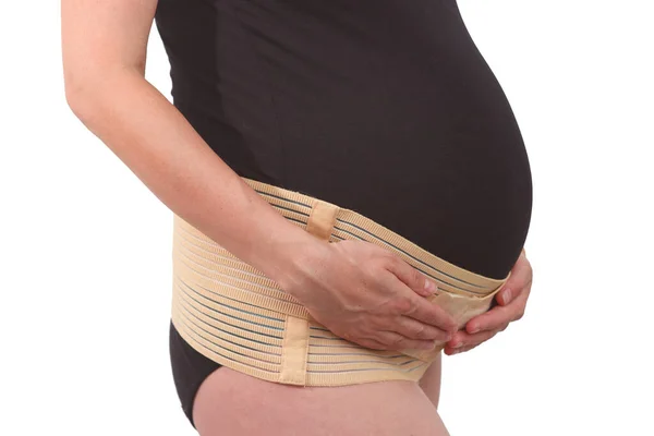 Belly of pregnant woman with elastic maternity band on white isolated background