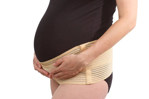 Belly of pregnant woman with elastic maternity band on white isolated background