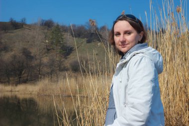 Caucasian woman sitting on a bench near the water.