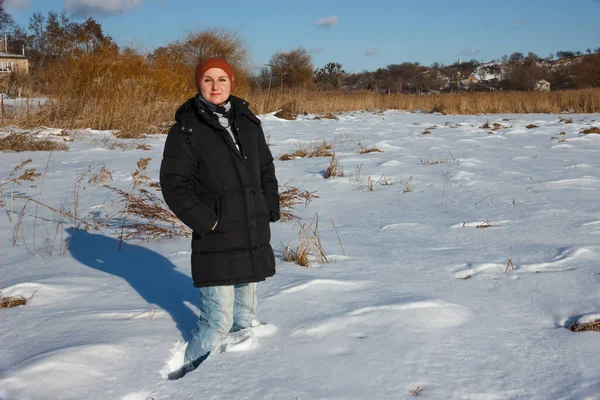 The girl in the brown hat and black jacket walks on a snow-covered field. Fell into the snow.