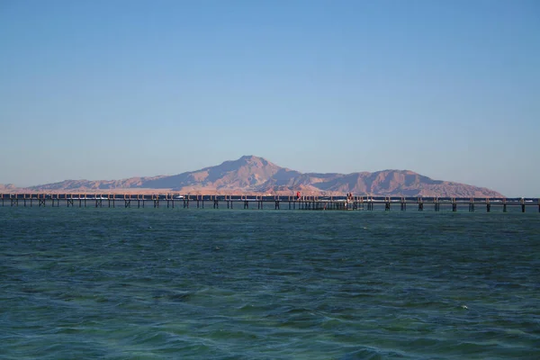 Pierce with people walking on it. Red Sea and beautiful mountains. Egyptian landscape. Long pier, sea and mountains.
