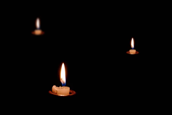 Three candles burning in the dark. The candles almost burned out.