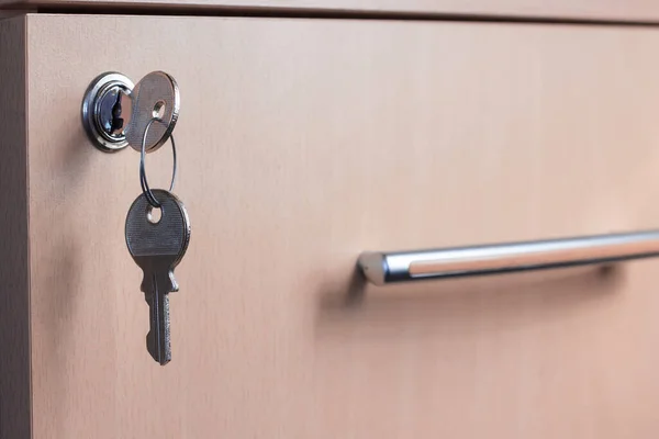 The key in the keyhole of the desk drawer