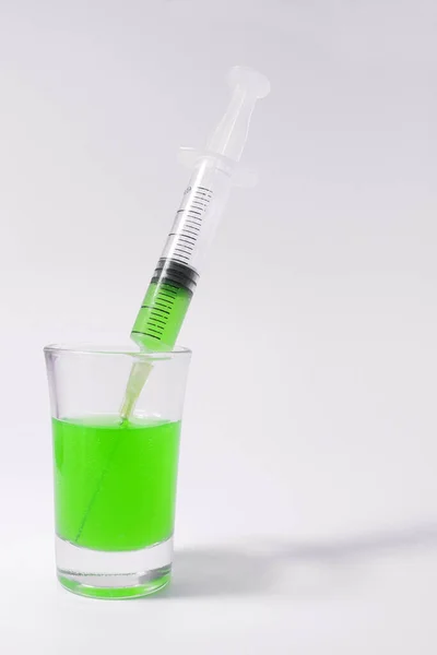 Syringe with green liquid on the white background. Syringe and glass on a white background. 