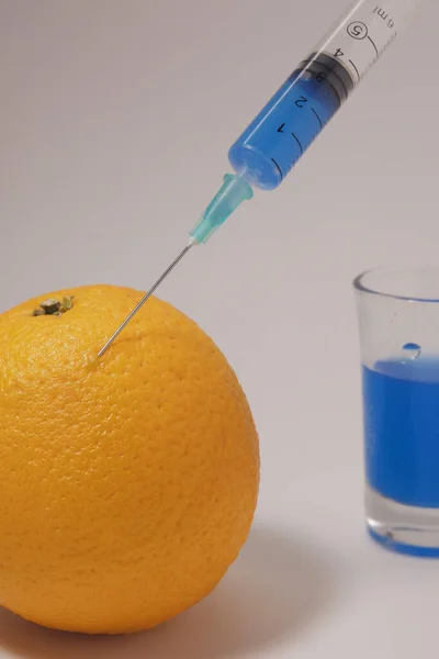 Injecting Blue Liquid Orange Fruit Orange Syringe Glass White Background — Fotografia de Stock