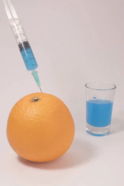 Injecting Blue Liquid Orange Fruit Orange Syringe Glass White Background — Stok fotoğraf