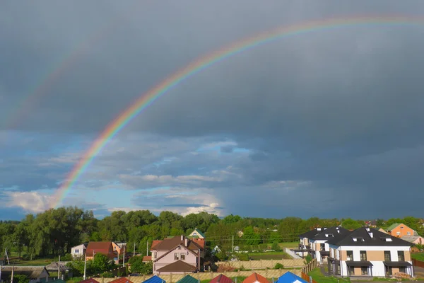 Beautiful big rainbow over rural houses. Rainbow after the rain. Ukrainian village.