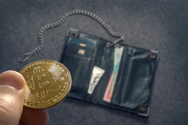 Bitcoin close up. Bitcoin in the foreground in focus against the background of a defocused wallet with money