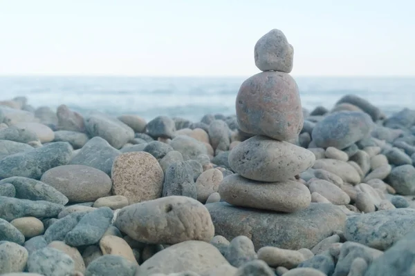 Pebbles on the sea coast. Little cairn on the background of the sea. Landscape for meditation. 