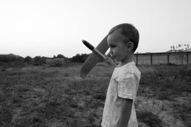 Monochrome photo. Little boy launches toy airplanes. Young aviator. The boy dreams of becoming an airplane pilot.
