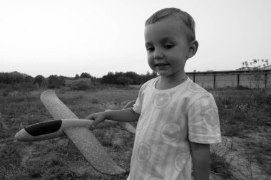 Monochrome photo. Little boy launches toy airplanes. Young aviator. The boy dreams of becoming an airplane pilot.