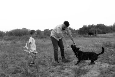 Monochrome photo. Mother with son and dog. A little boy and his mother are walking the dog. Happy family on a walk.