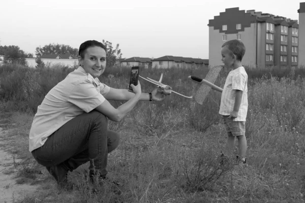 Tek renkli bir fotoğraf. Küçük çocuk ve annesi oyuncak uçakları fırlatıyorlar. Genç havacı. Çocuk bir uçak pilotu olmayı hayal ediyor..