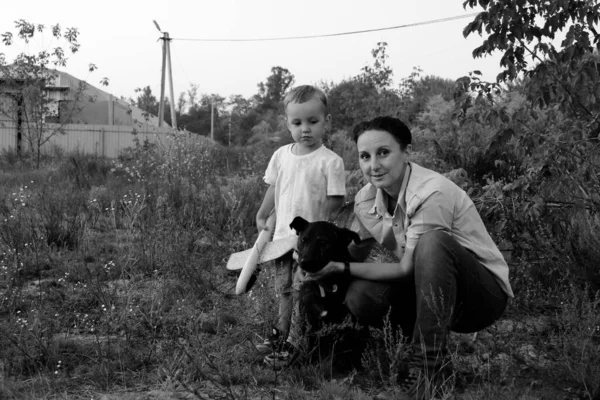 Monochrome photo. Mother with son and dog. A little boy and his mother are walking the dog. Happy family on a walk.