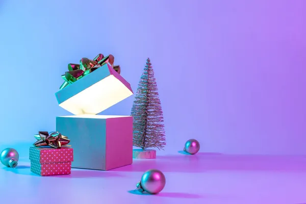 ネオンクリスマス冬の背景 輝きのライト 最小限の木とクリスマスギフトボックスを開きます ネオン抽象的なグラデーションの背景に休日の装飾バブルボール ハッピーニューイヤーコピースペース — ストック写真