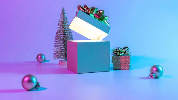 クリスマスプレゼントボックスネオン背景 輝きのライト 最小限の木とXmasのギフトボックスを開きます ネオン抽象的なグラデーションの背景に休日の装飾バブルボール ハッピーニューイヤーコピースペース — ストック写真