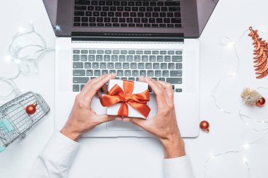 Çevrimiçi Noel. Hediye kutusu kırmızı kurdele, tramvay ve dizüstü bilgisayar, düz konumda internet alışveriş kompozisyonu. Kış Xmas tatil satışları