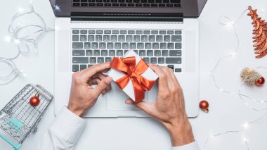 Noel indirimi. Hediye kutusu kırmızı kurdele, tramvay ve dizüstü bilgisayar internette online alışveriş kompozisyonu olarak yatıyordu. Hediye al, Noel 'e hazırlan, hediye kutuları ve paketler arasında.