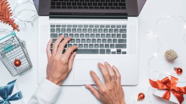 Çevrimiçi Noel. Hediye kutusu kırmızı kurdele, tramvay ve dizüstü bilgisayar, düz konumda internet alışveriş kompozisyonu. Kış Xmas tatil satışları