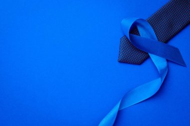 Kasım. Mavi kurdele, koyu mavi arka planda izole edilmiş moda kravatı. Kasım ayında erkek sağlığının prostat kanseri olduğunun farkındalığı. Yaşayan ve hastalıklı insanlara destek olmak